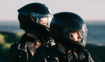 Couple sitting on a motorcycle wearing helmets