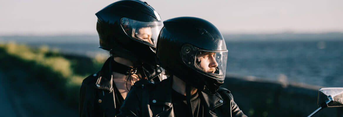 Couple sitting on a motorcycle wearing helmets