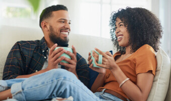 Couple sitting on living room couch drinking tea